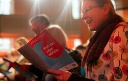 Eröffnungsgottesdienst von Brot für die Welt - Besucherin mizt dem Liederheft